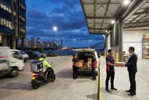 Courier coordinating cream charger deliveries outside a Sydney warehouse at night
